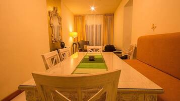 A hotel room with a dining table, chairs, a sofa, a lamp, and a decorative mirror.