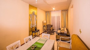 A hotel room with a dining table, chairs, a sofa, a lamp, and a large mirror on the wall. - Arathi Appartment (Galle)