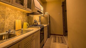 A compact kitchen with a gas stove, a refrigerator, and a sink. - Arathi Appartment (Galle)