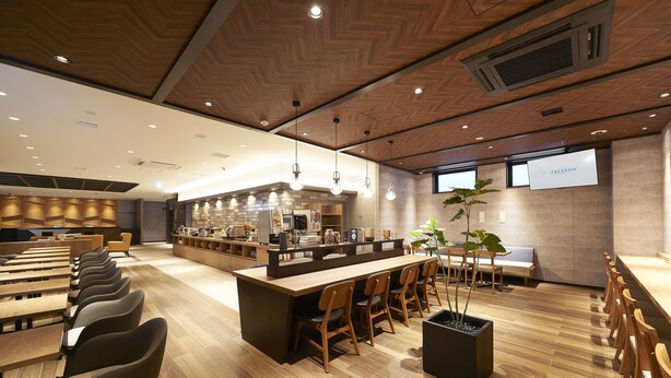 Un restaurante moderno con una barra larga, varias áreas de estar y un panel de menú visible.