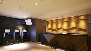 Un área de recepción de diseño moderno, con un mostrador de recepción, un espacio de descanso y un televisor montado en la pared.