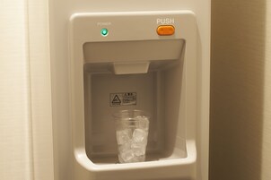 A water dispenser with a cup of ice and a warning label.