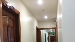 A hallway with a wooden door labeled "203" and a mirror reflecting the interior. - Nhat Tan Hotel (Quy Nhon)