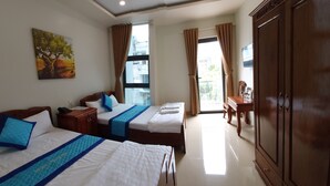 A hotel room with two beds, a wooden wardrobe, a desk, and a painting on the wall. - Nhat Tan Hotel (Quy Nhon)