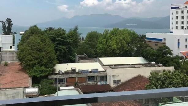A view of a residential area with buildings, trees, and a distant mountain range. - Nhat Tan Hotel (Quy Nhon)