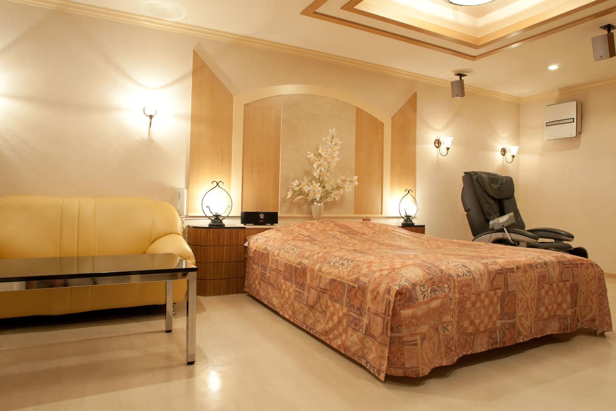 Habitación de hotel con cama, sofá, escritorio y sillón de masaje.