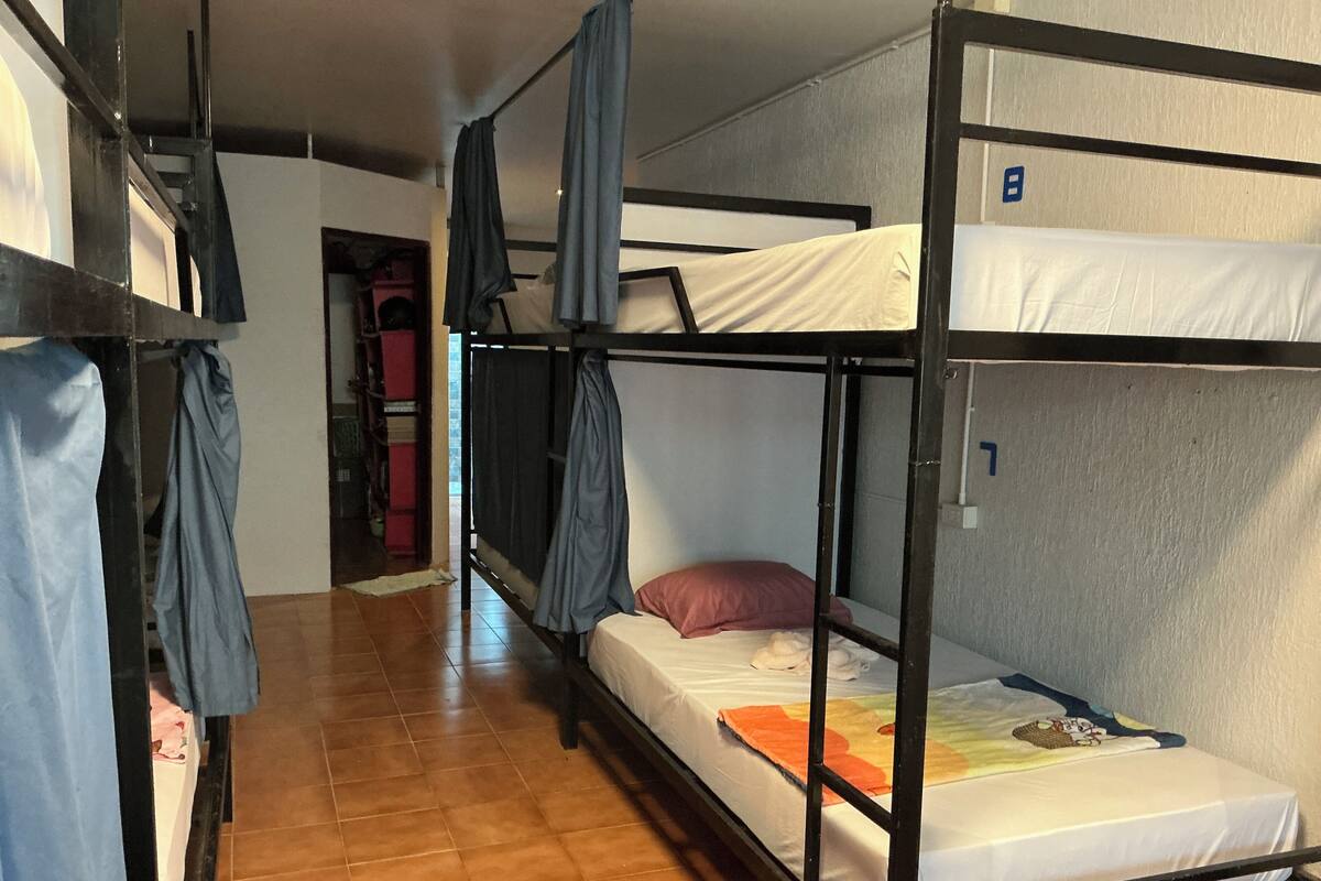 A dormitory room with bunk beds, a tiled floor, and a door leading to another room.