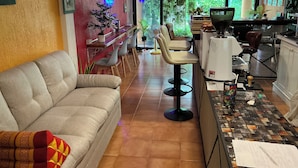 Eine Hotelhalle mit einer Couch, einer Bar, Stühlen und einer Kaffeemaschine.