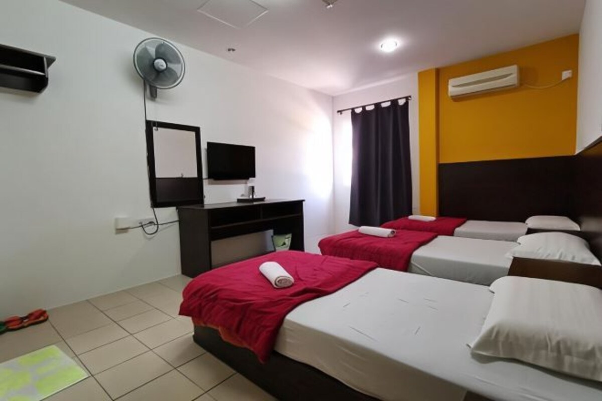 A hotel room with two beds, a desk with a computer, a TV, and an air conditioner.