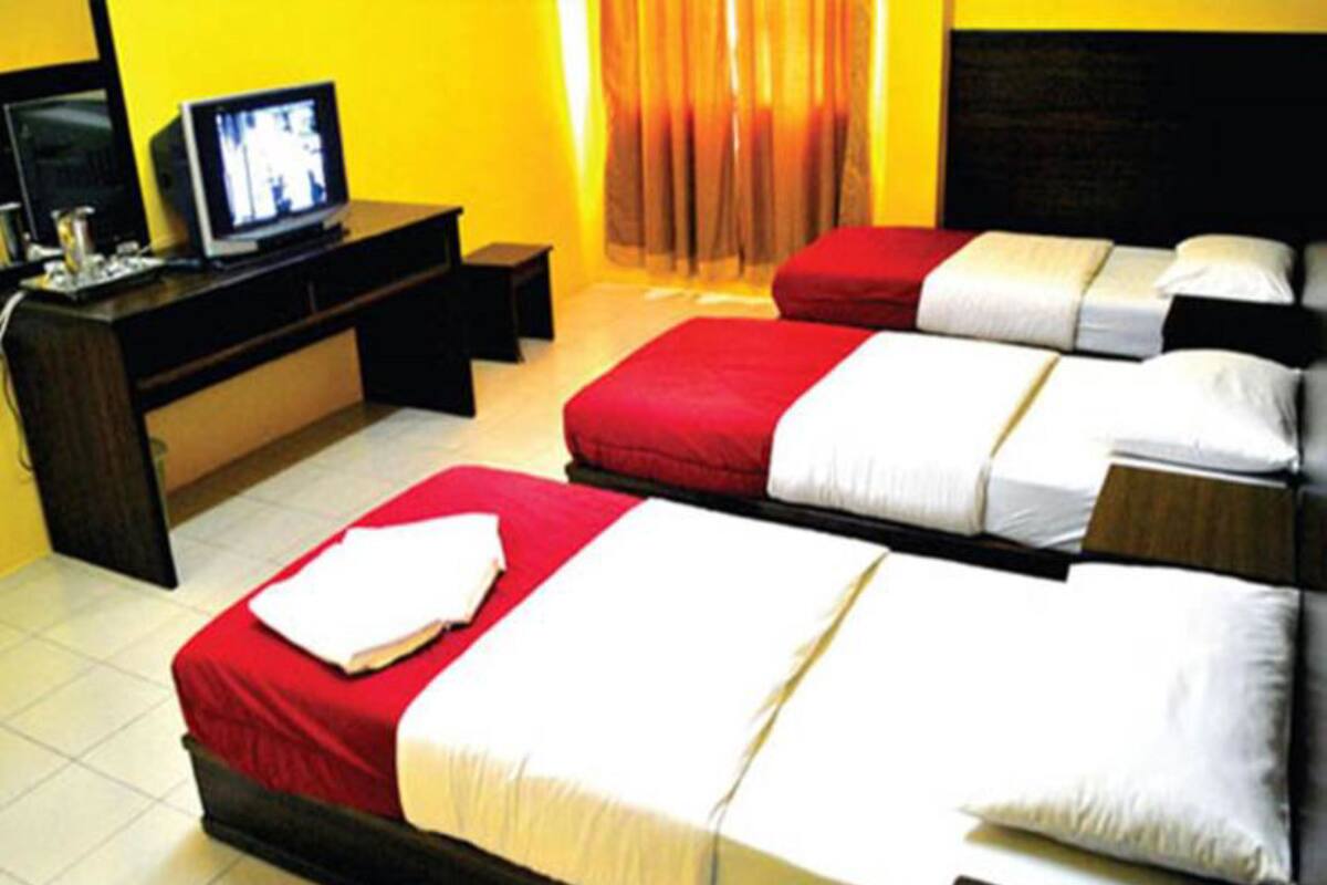 Habitación de hotel con dos camas, un televisor sobre un escritorio y una ventana con cortinas.