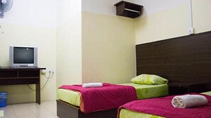Una habitación con dos camas, un escritorio con computadora y un ventilador de pared.