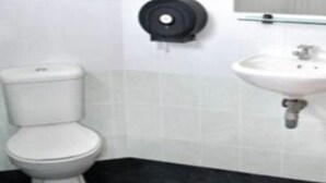 Un baño con inodoro, lavamanos y secamanos.