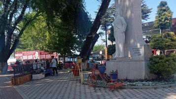 Una plaza pública con una estatua, bancos y una bicicleta.