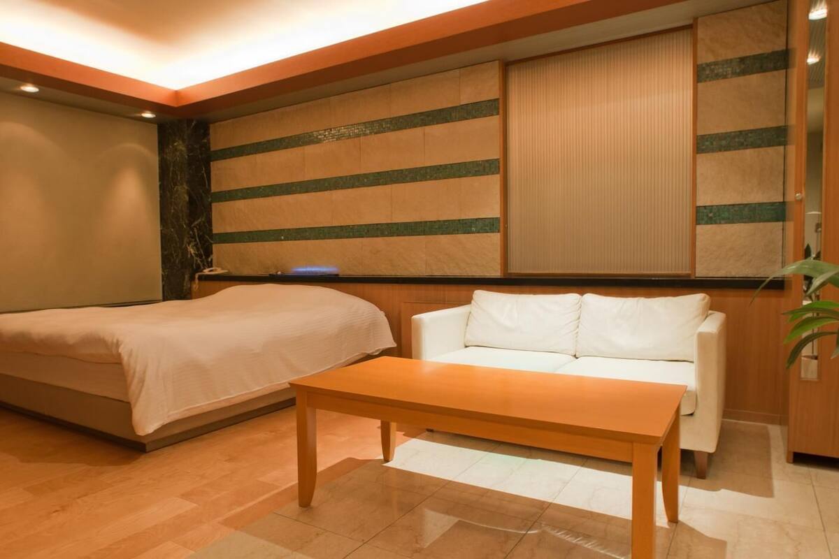 Une chambre d’hôtel avec un lit, un canapé et une table en bois.