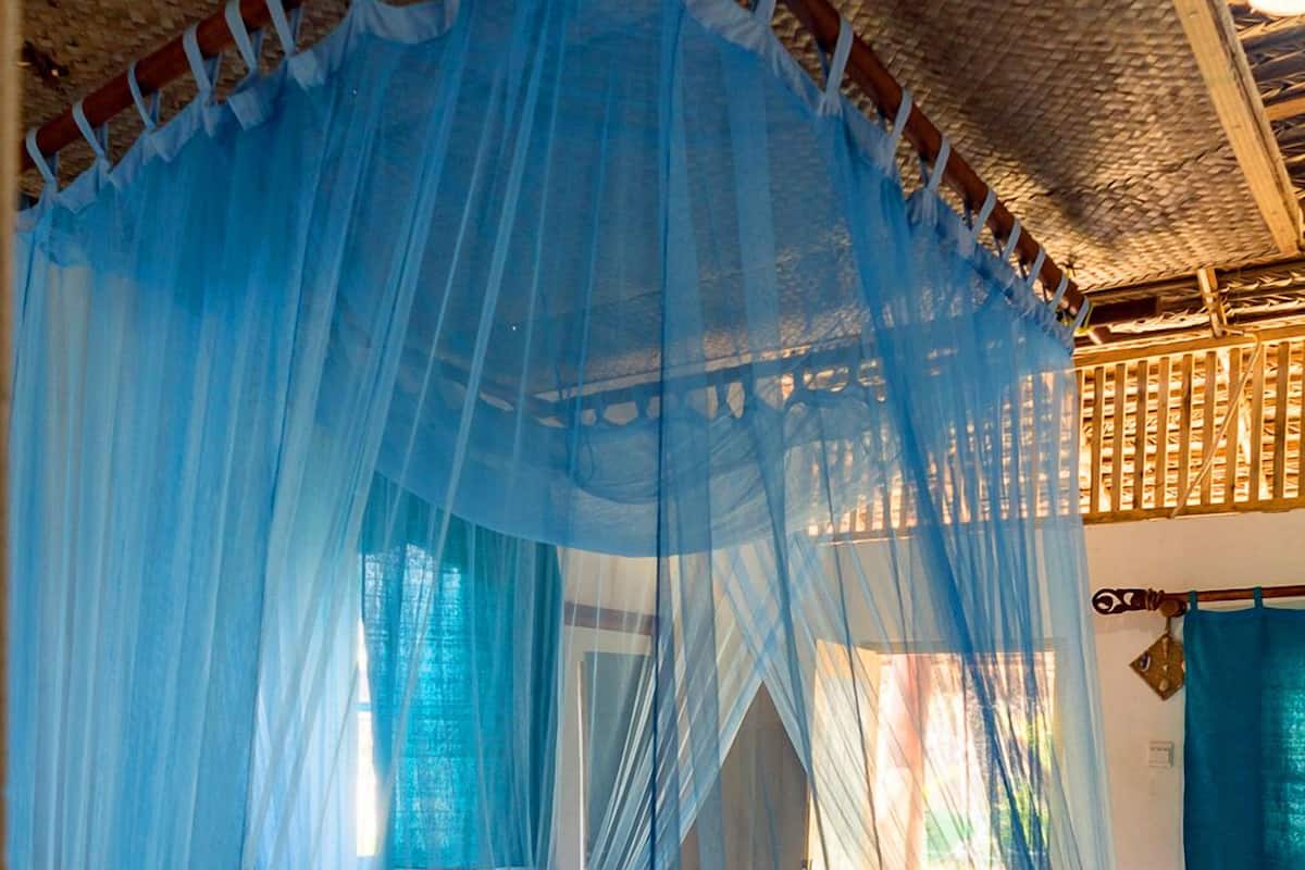 A room with a canopy bed, a woven ceiling, and a wooden lattice structure.