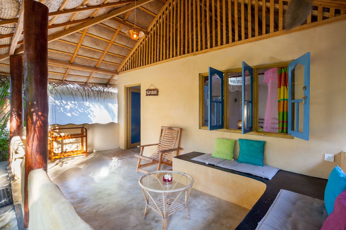A room with a thatched roof, a wooden chair, a sofa, and a small table.