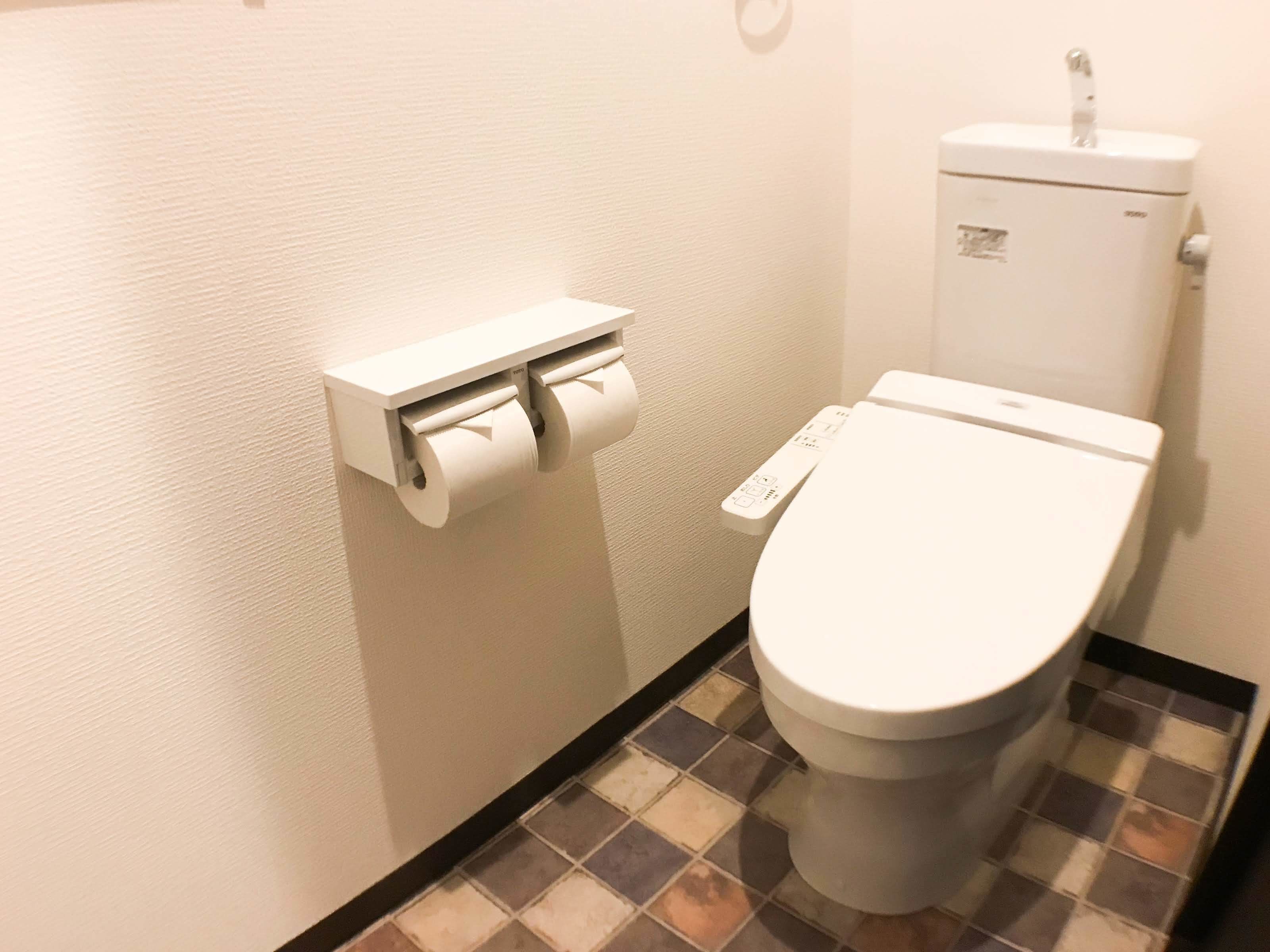 A toilet with a flush handle and a paper towel dispenser.