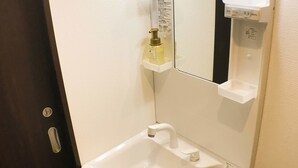 A small bathroom with a white sink, a mirror, and a soap dispenser on a small shelf. - GH One More Heart Jujo 1 (Kyoto)