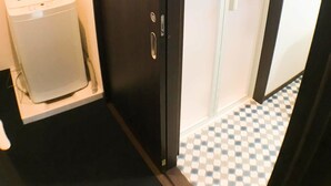 A room with a dark wooden wardrobe, a white washing machine, and a checkered floor. - GH One More Heart Jujo 1 (Kyoto)