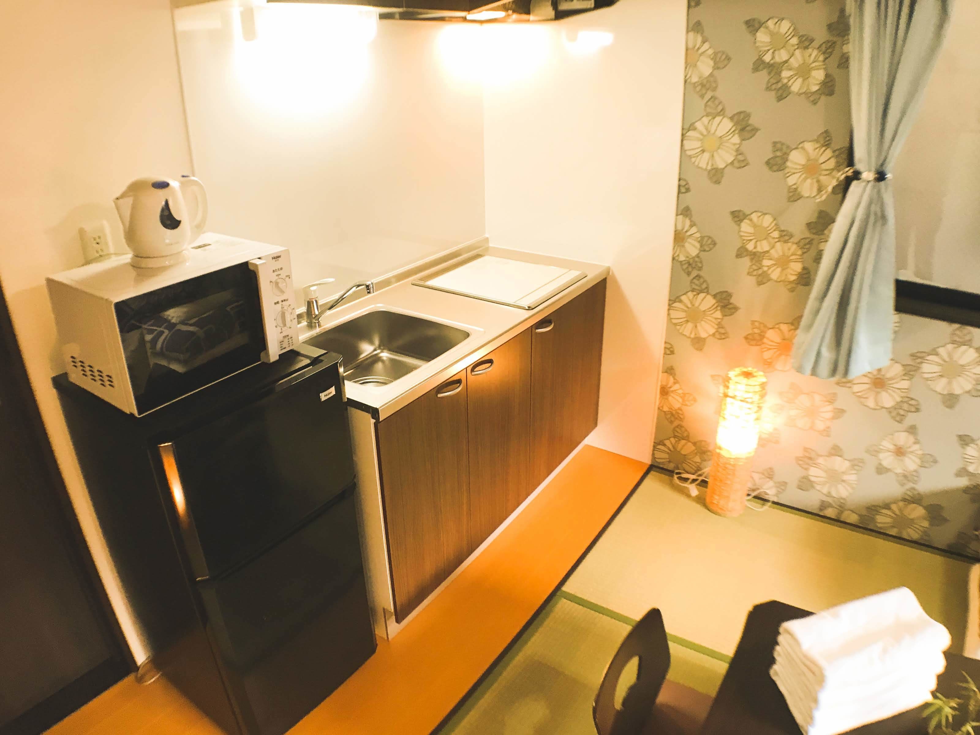 A compact kitchen with a microwave, sink, and a small refrigerator.