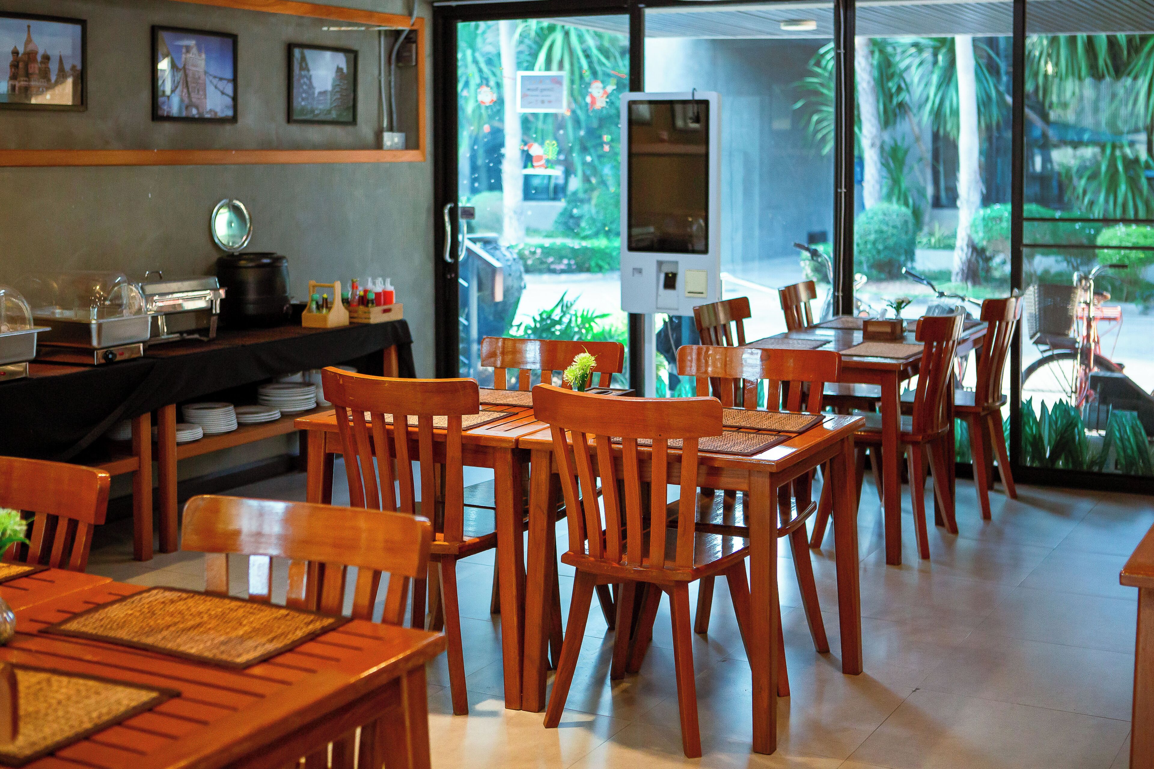 Een restaurant met houten meubels, een buffetgedeelte en uitzicht op groen.