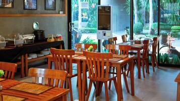 A restaurant with wooden furniture, a buffet area, and a view of greenery outside.