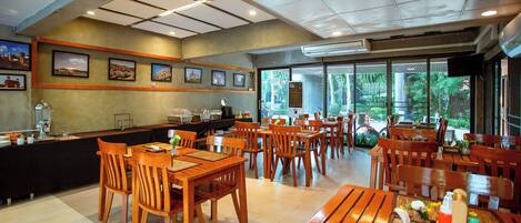Un restaurante con mesas y sillas de madera, una barra con menú y cuadros en la pared.