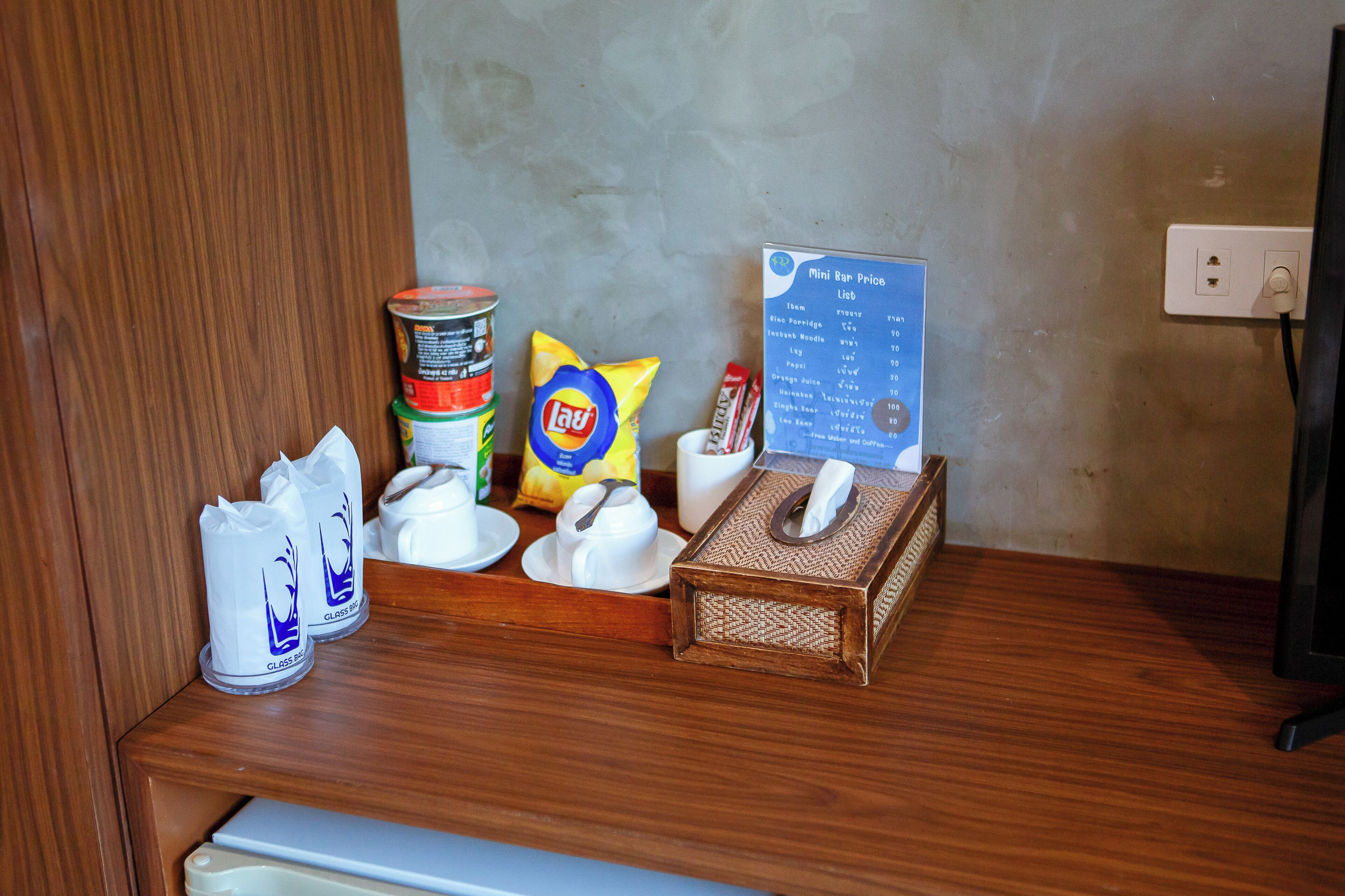 A wooden counter with a menu, a can of food, a bag of chips, a tissue box, and a cup.