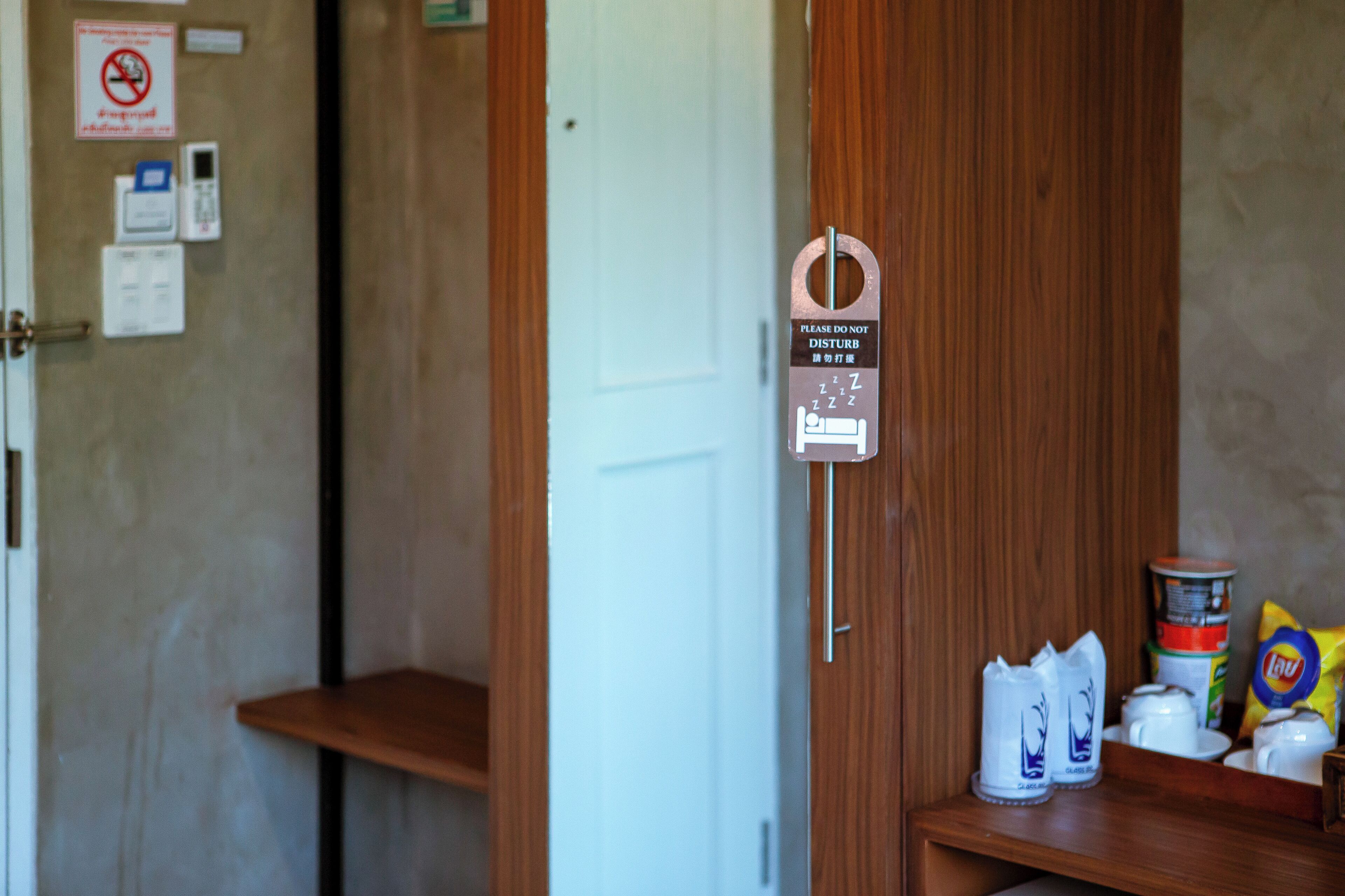 A wooden door with a sign indicating a quiet room. There are shelves with various items including a can, a bag of chips, and a cup.