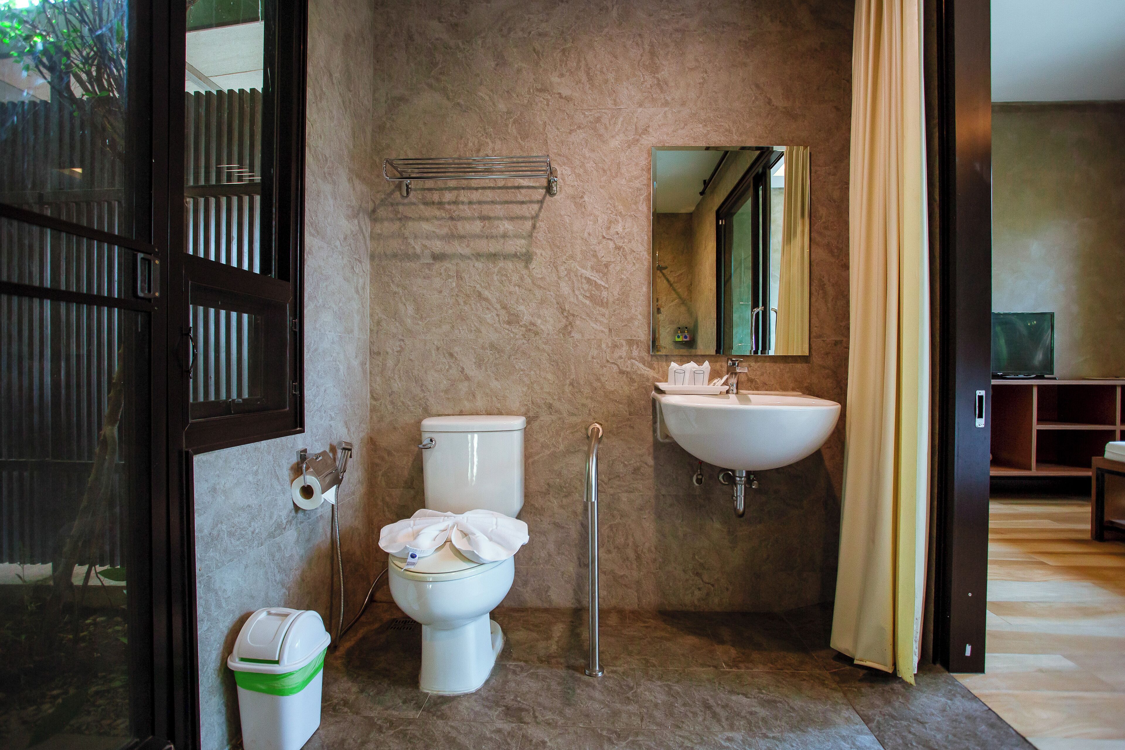 A bathroom with a toilet, sink, and mirror.