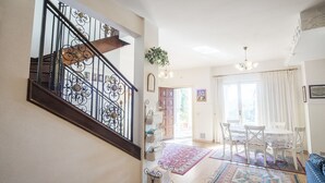 A staircase with ornate metal railings, a dining area with white chairs and a table, and a hallway with a mirror and a potted plant. - Casale dell'Insugherata B&B Roma (Rome)