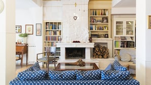 A living room with a fireplace, bookshelves, a sofa, and a dining area. - Casale dell'Insugherata B&B Roma (Rome)