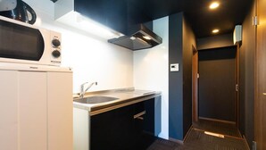 Una cocina compacta con un microondas Haier, un lavamanos y una campana extractora negra.