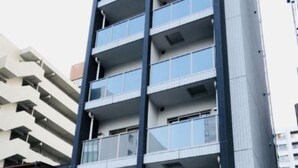 Un edificio de varios pisos con balcones, una entrada con azulejos y una puerta visible.