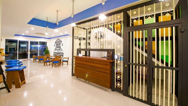 A hotel lobby with a reception desk, seating area, and a decorative gate. - The Pho Thong Phuket (Phuket)
