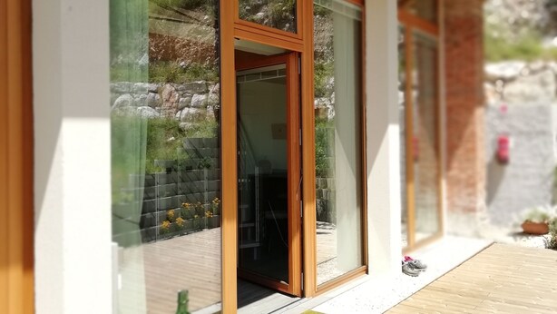 A modern building with large glass windows and wooden beams. - Agriturismo Podere Nigriano (Salò)