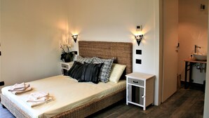 A neatly made bed with a headboard, bedside tables, and wall-mounted lights. - Agriturismo Podere Nigriano (Salò)