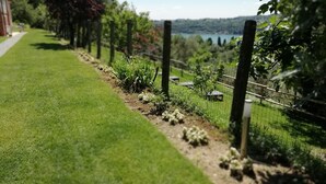 A well-maintained garden with a clear path, a fence, and a view of a lake and hills in the distance. - Agriturismo Podere Nigriano (Salò)