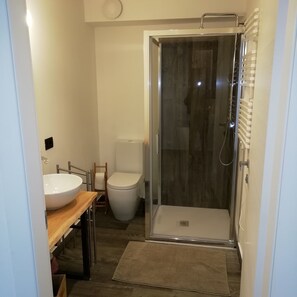 Ein modernes Badezimmer mit einer Duschkabine, einer weißen Toilette und einem Holzbadezimmer-Möbel mit Waschbecken.