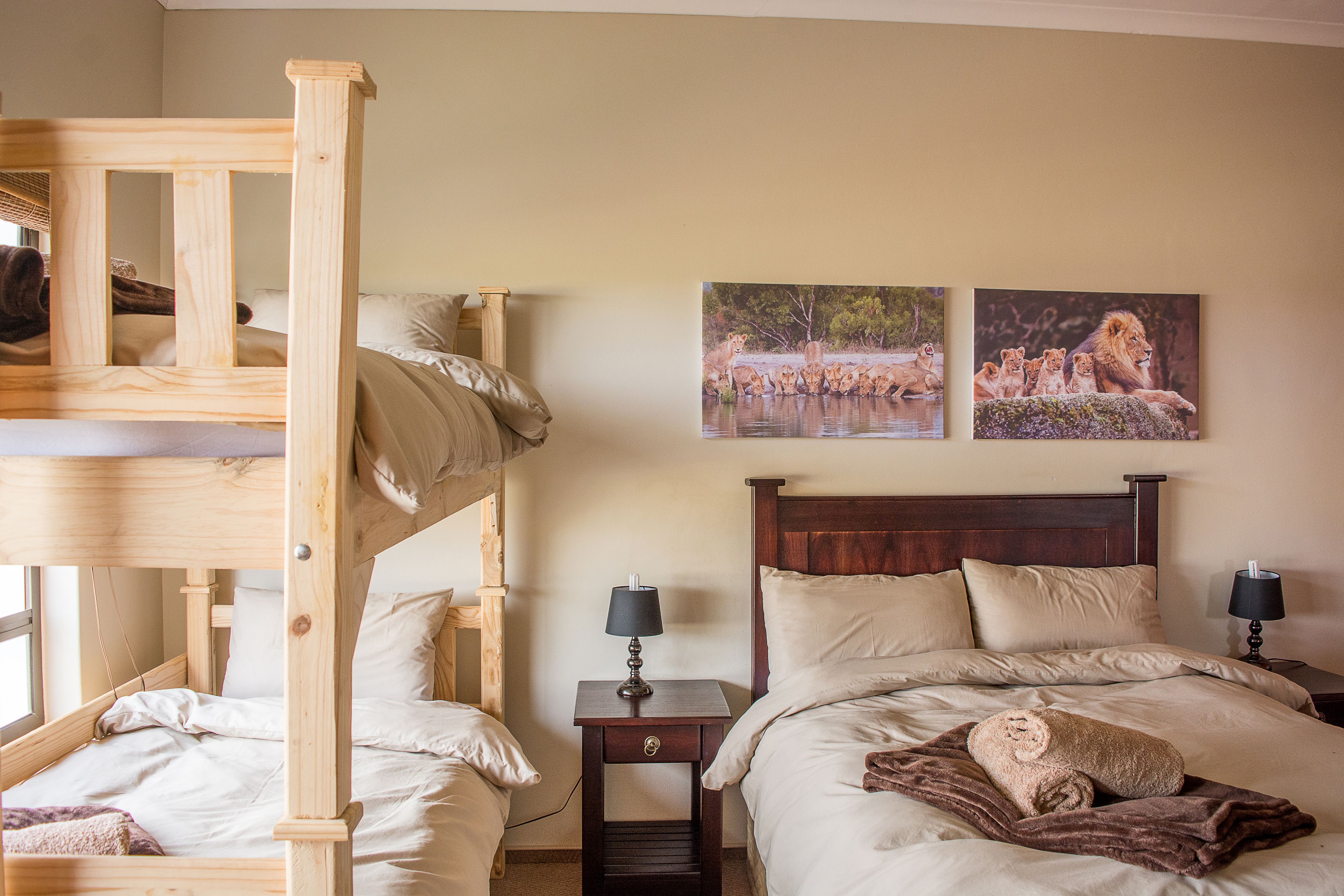 Ein Hotelzimmer mit Etagenbett, einem Einzelbett, zwei Nachttischen mit Lampen und zwei gerahmten Bildern an der Wand.