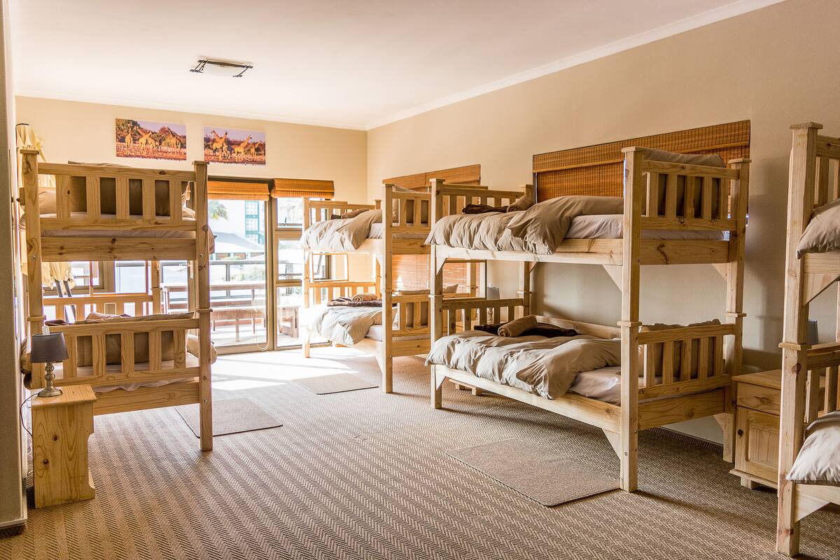 A dormitory room with bunk beds, a desk, and a chair.
