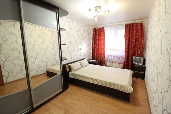 Relax in a serene bedroom with a large bed, bedside table, and wardrobe, perfect for unwinding.