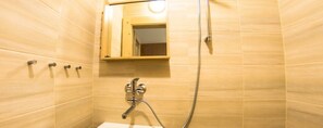 Un baño con ducha, espejo y lavabo.