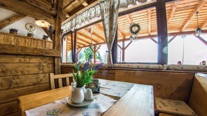 Un intérieur en bois avec une table en bois, un vase rempli de fleurs et une fenêtre avec des rideaux.