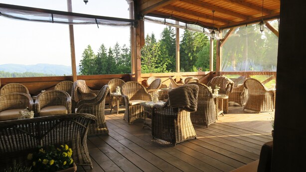 Un espace extérieur aménagé, abrité et doté de mobilier en osier, offrant une vue sur les montagnes.