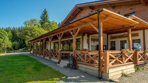 Un bâtiment en bois doté d’un patio couvert, avec des panneaux indiquant « Horsky Hotel » et une enseigne à l’extérieur.