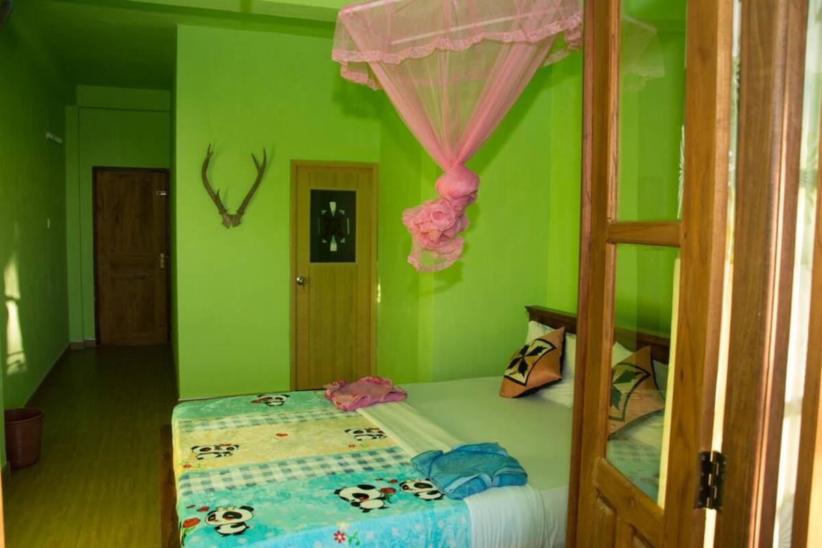 A room with a bed, a door, and a wall-mounted deer head decoration.