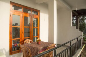 A dining area with a table and chairs, a wooden-framed window, and a balcony railing. - The Onestar Homestay (Ella)