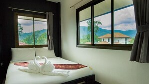 Una habitación de hotel con cama, dos ventanas y vistas a casas y montañas.