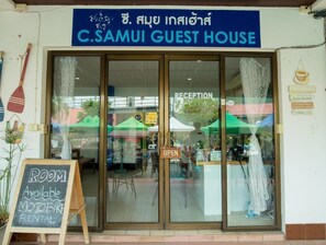 The entrance to C. Samui Guest House with a reception area visible through the glass doors.